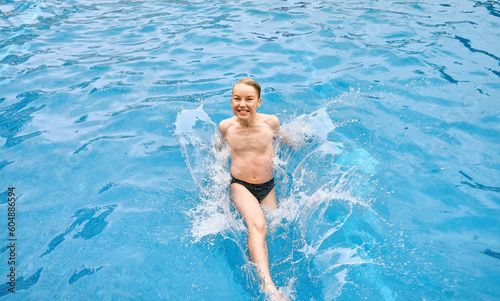 Child jump, swim in the pool outdoors, sunbathes, swimming in hot summer day. Relax, Travel, Holidays, Freedom concept. 