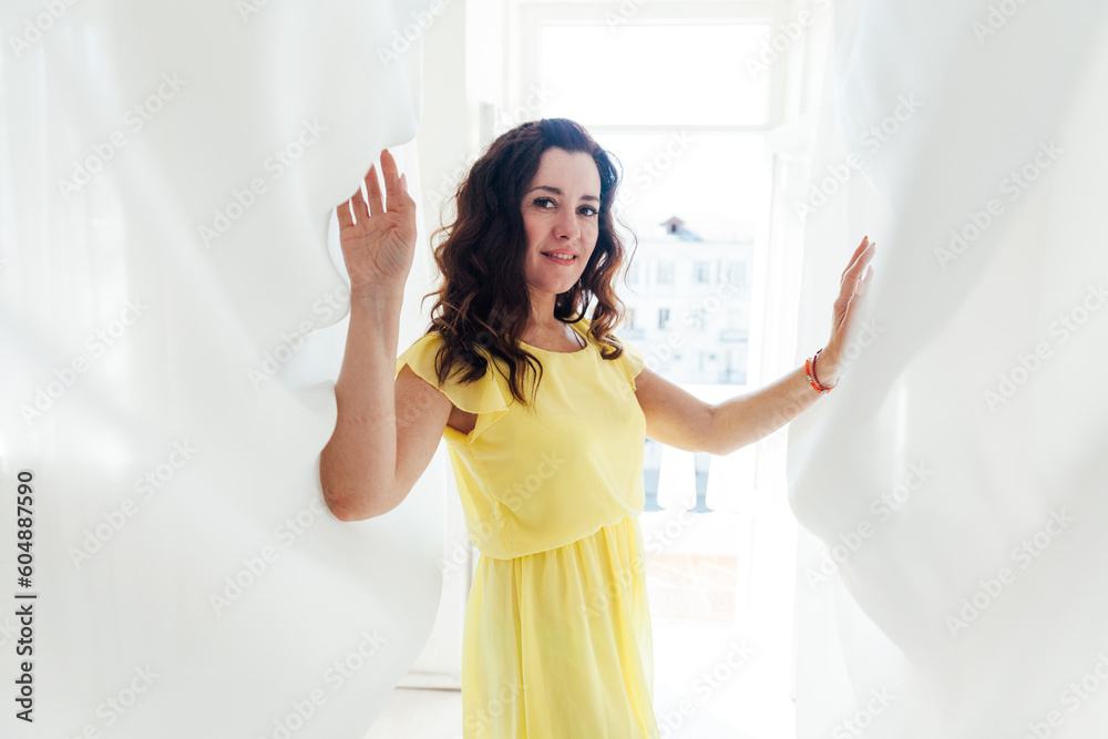beautiful brunette woman in yellow dress standing in white fabrics beautiful brunette woman in yellow dress standing in white fabrics