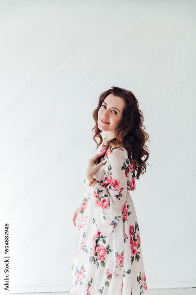 a brunette woman in a floral dress poses in a bright room a brunette woman in a floral dress poses in a bright room