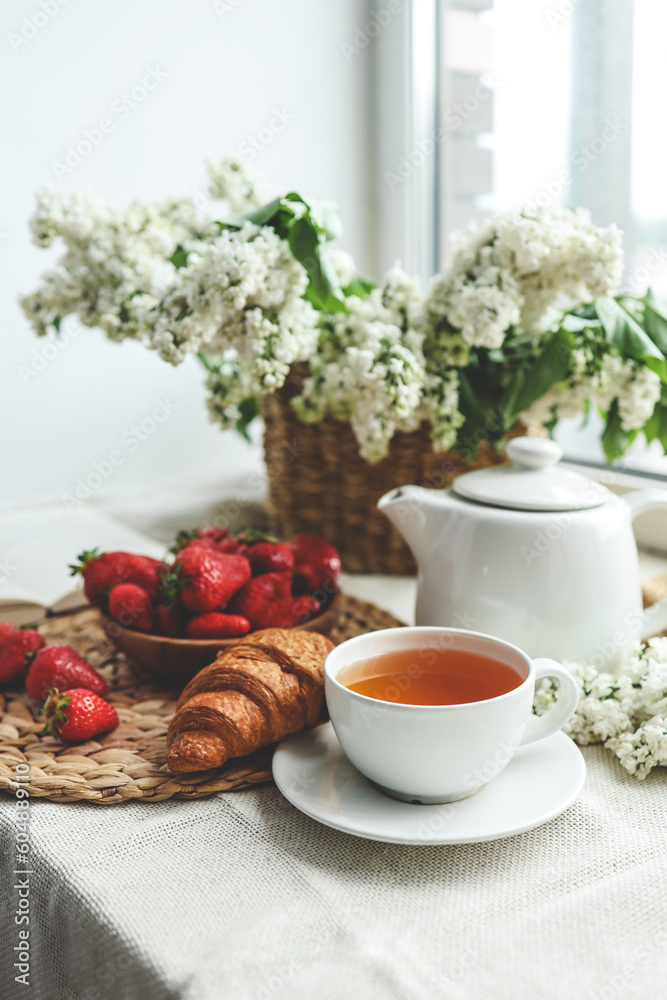 Cup of tea, croissant, strawberry and lilac basket, summer morning aesthetic Cup of tea, croissant, strawberry and lilac basket, summer morning aesthetic