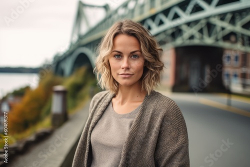 Environmental portrait photography of a glad girl in her 30s wearing a chic cardigan against a picturesque bridge background. With generative AI technology