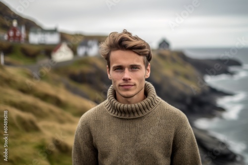 Medium shot portrait photography of a glad boy in his 30s wearing a cozy sweater against a scenic cliffside village background. With generative AI technology