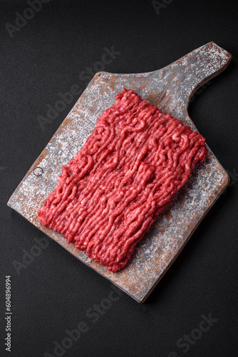 Raw ground beef or pork on a wooden cutting board with spices and salt