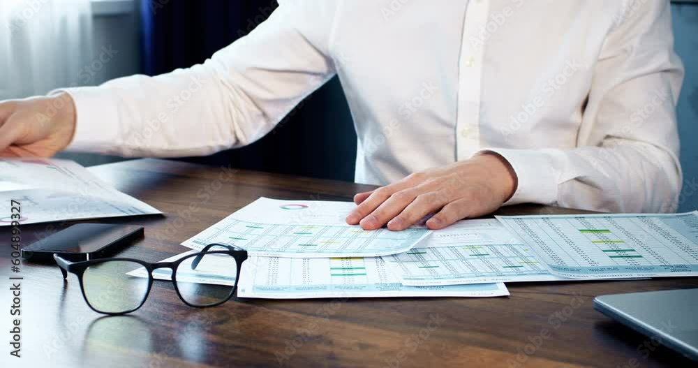 The trader sorts through important papers with numbers and data, financial monitoring on paper. The trader sorts through important papers with numbers and data, financial monitoring on paper.