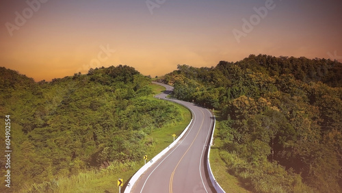 The sunset view with highway stairs to the sky of road trough with green forest as the nature landscape background