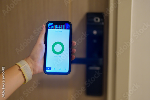 Hand using smartphone for open digital door lock at home or apartment. NFC Technology, Fingerprint scan, keycard, PIN number, smartphone, electrical and contactless lifestyle concepts photo
