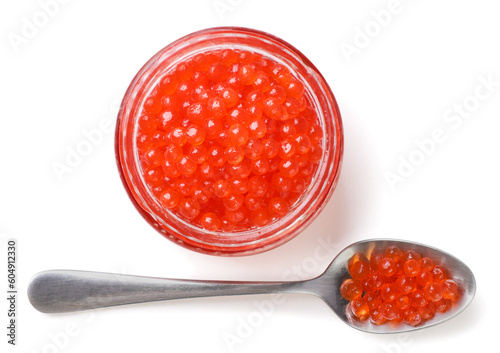 Red caviar in a glass jar and a spoon on a white background. Top view