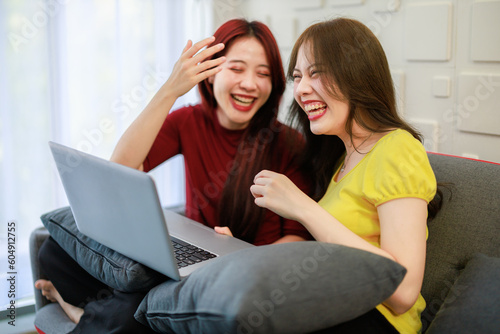 Female couple enjoying time together on a sofa. working with computer laptop.