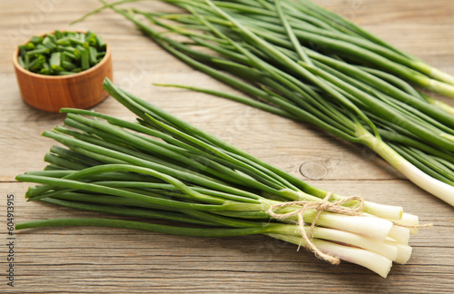 Fresh green onions on a cutting board on grey wooden background.