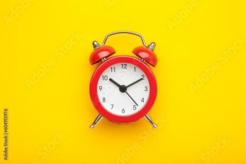 Red vintage alarm clock on yellow background. Space for text