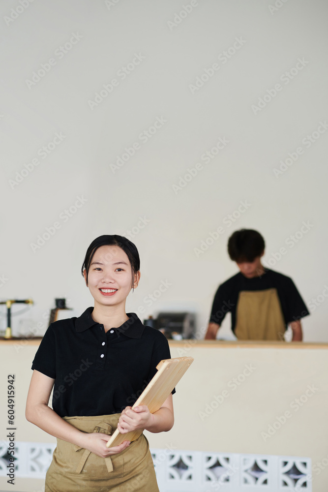 Smiling young Vietnamese cafe waitress with serving wooden board