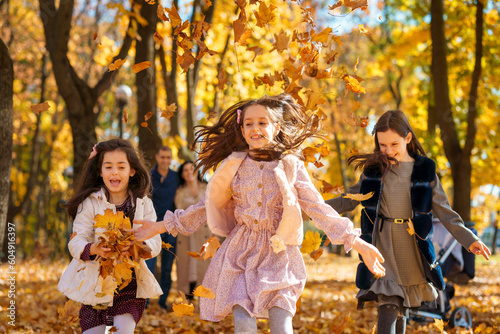 happy children playing together and scattering yellow leaves, portrait of big family in autumn city park, children running with armful of leaves, beautiful nature, bright sunny day