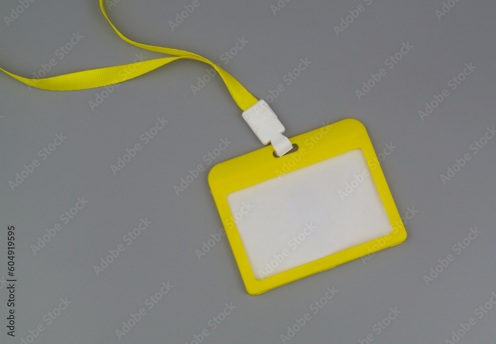 Yellow blank badge with string on grey background.