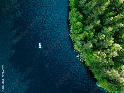 Aerial view fishing boat in blue lake and green woods in Finland