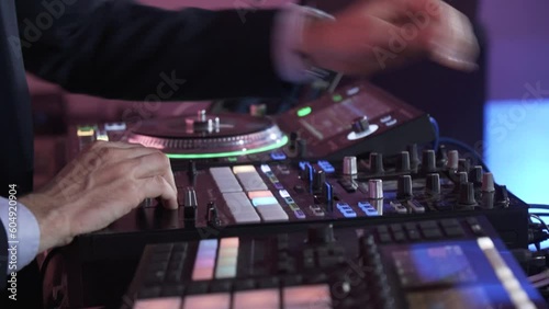 A DJ works on his sound mixing board at an event - closeup