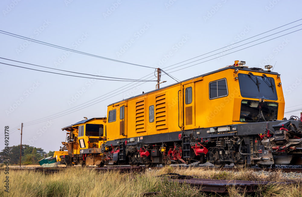 Low angle view of yellow train stationary on grassy track near station. Low angle view of yellow train stationary on grassy track near station.