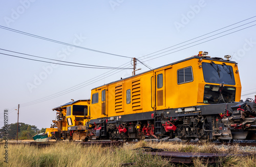 Low angle view of yellow train stationary on grassy track near station.