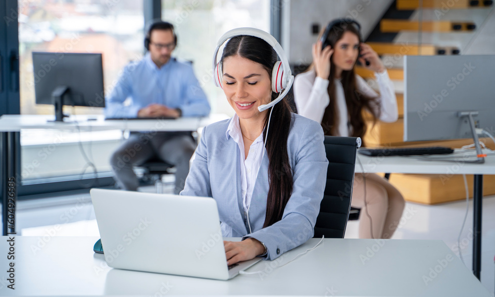 Professional woman with headset: customer support agent providing efficient assistance with laptop in call center environment Professional woman with headset: customer support agent providing efficient assistance with laptop in call center environment