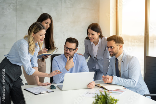 Group of professional business people engaging in a productive office meeting  using laptop while working together on a project.