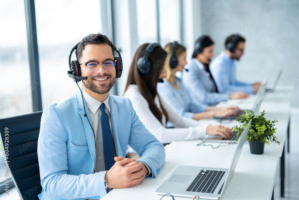 Portrait of confident bearded call center operator man sitting at workplace. Call center concept Portrait of confident bearded call center operator man sitting at workplace. Call center concept