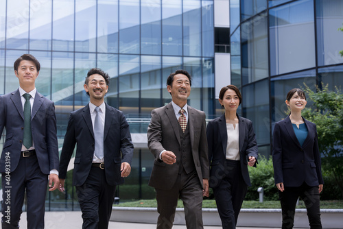 オフィスを背景にスーツを着て颯爽と歩くカッコいい日本人(アジア人）ビジネスマンチームのイメージ　上半身　コピースペースあり © kapinon