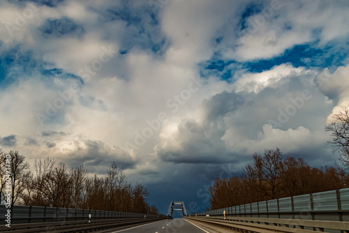 Winter landscape with dramatic clouds and a bridge on a sunny day near Plattling, Isar, Deggendorf, Bavaria, Germany