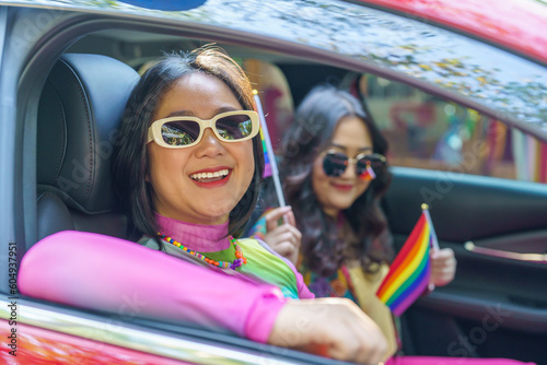 Happy Asian woman support LGBT pride parade in car. with Rainbow of LGBTQ or LGBTQIA  