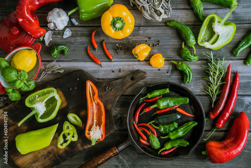 a colorful assortment of peppers, hot peppers and chili, decorated with various assesoires on a wooden table. photo