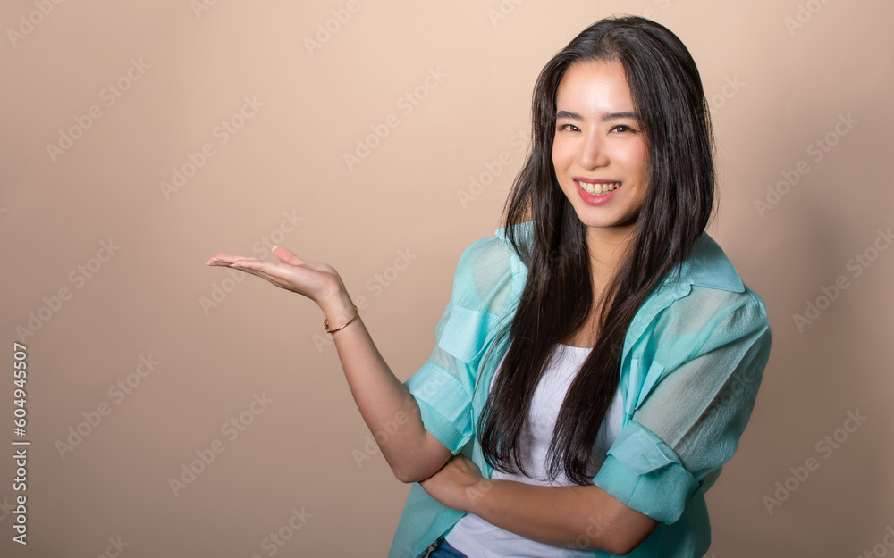 Asian beautiful woman wearing casual clothes, smiling with confidence, happiness, looking at camera, raising hand to show or present blank copy space on isolated background for advertisement. Asian beautiful woman wearing casual clothes, smiling with confidence, happiness, looking at camera, raising hand to show or present blank copy space on isolated background for advertisement.
