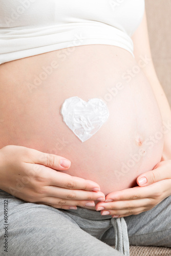 Wallpaper Mural a pregnant girl sits at home on the bed and smears heart an anti-stretch mark cream on her stomach. Pregnancy, motherhood, preparation and expectation concept Torontodigital.ca