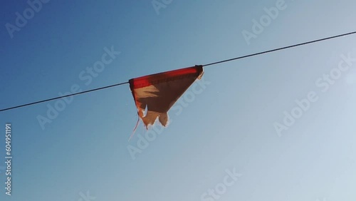 A closeup video of the old torn red protective flag on a rope on the blue sky background