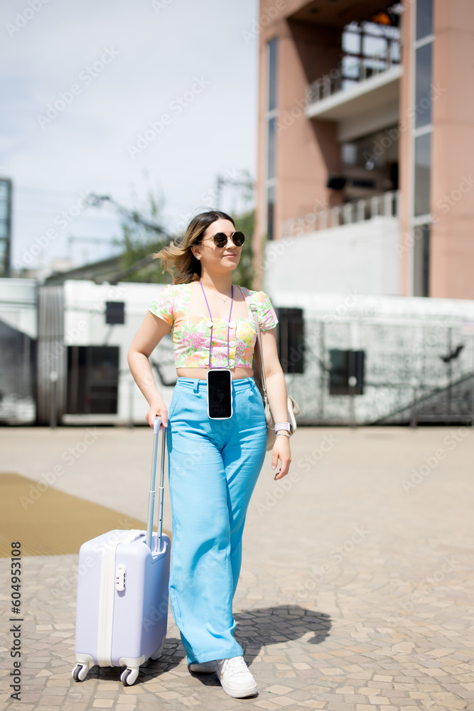 Happy tourist at the train station walking with suitcase, summer vacation concept