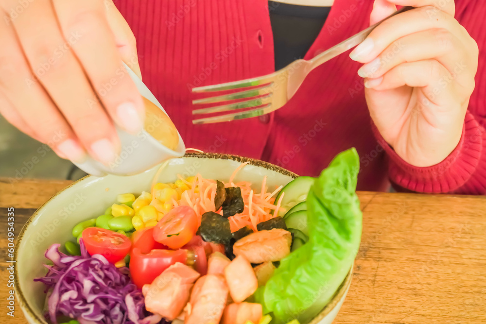 A woman is eating a salmon salad with toasted sesame dressing with a fork. Concept for healthy food, fat loss, weight loss, diet menu, vegetarian vegan, whole organic food, omega-3, dietary fiber.