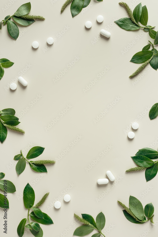 Seasonal spring allergies, fresh spring blooming branches tree with green new leaves and antihistamine pills on beige background, top view frame with copy space, Seasonal allergy concept
