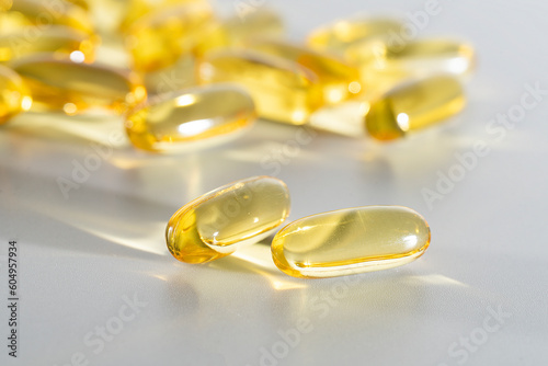 Fish Oil Omega 3 on white background, vitamin D yellow supplement gel capsules, macro shot 