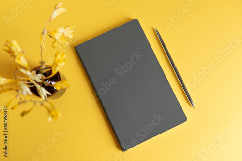 notebook and pen with yellow flowers on the yellow background
