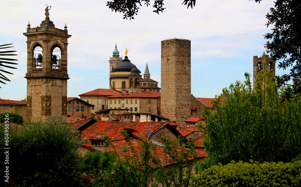 View of the church, bell towers and towers surrounded by greenery in the historic part of the city of Bergamo in northern Italy