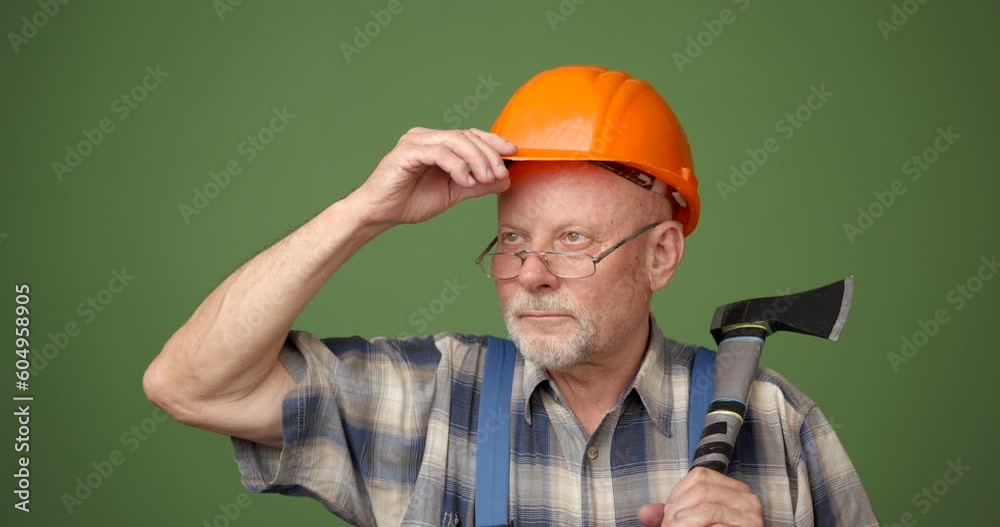 Mature man builder posing on a green background in studio