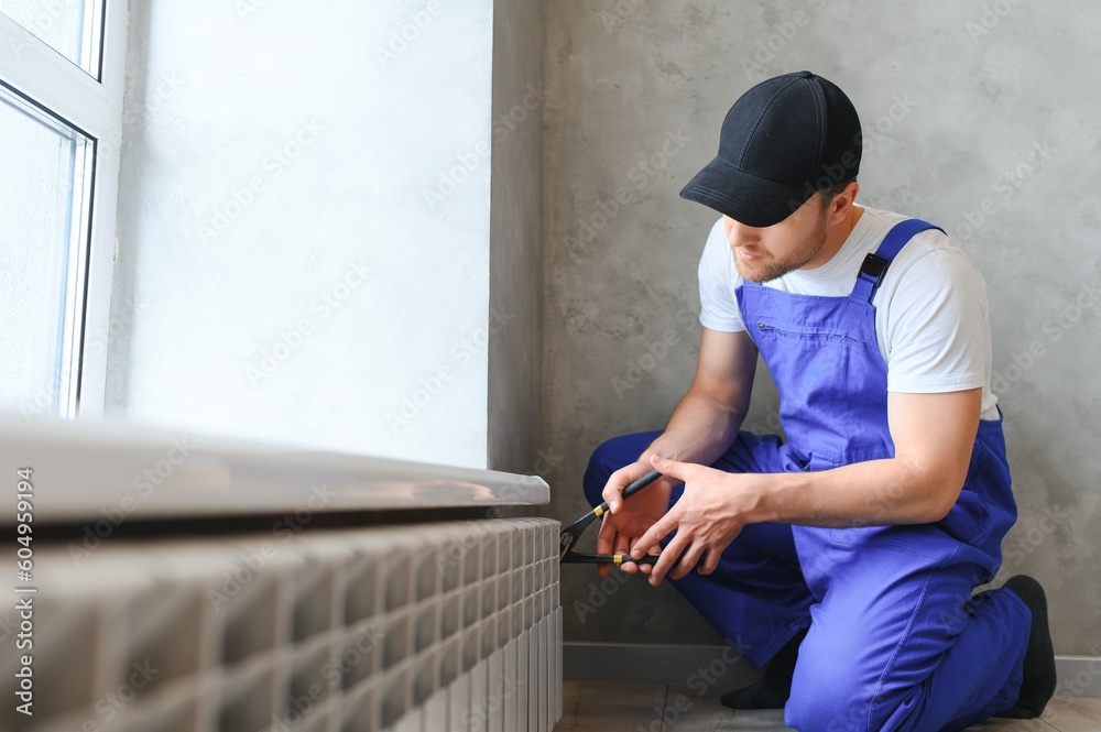heating system installation and maintenance service. plumber installing radiator. heating system installation and maintenance service. plumber installing radiator.