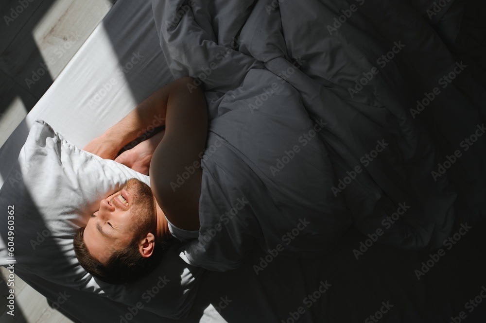 Handsome man sleeping under soft blanket in bed at home Handsome man sleeping under soft blanket in bed at home