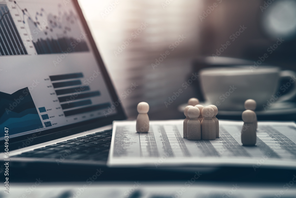 The wooden doll represents the employee of the company and them on laptop in workplace. Corporation, Enterprise concept. The wooden doll represents the employee of the company and them on laptop in workplace. Corporation, Enterprise concept.