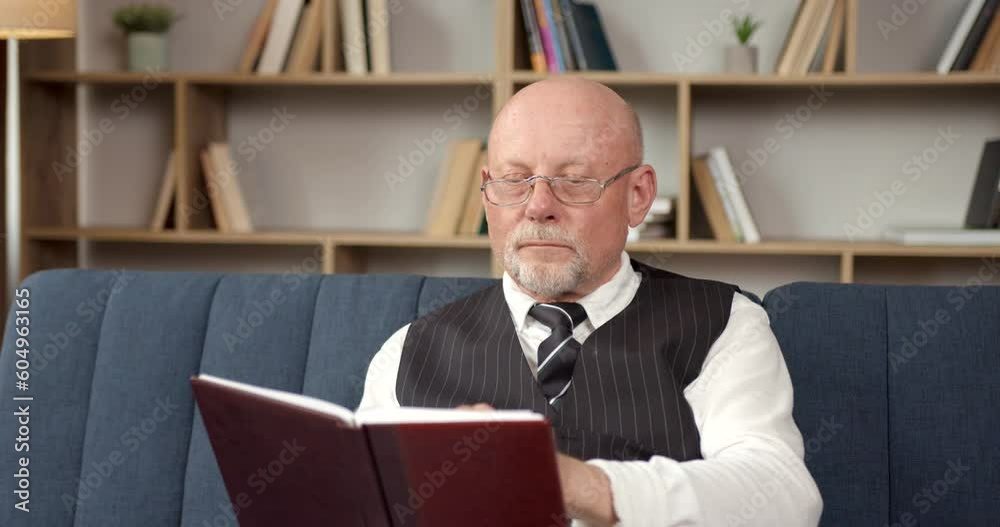 Senior man in a vest reading in the living room Senior man in a vest reading in the living room