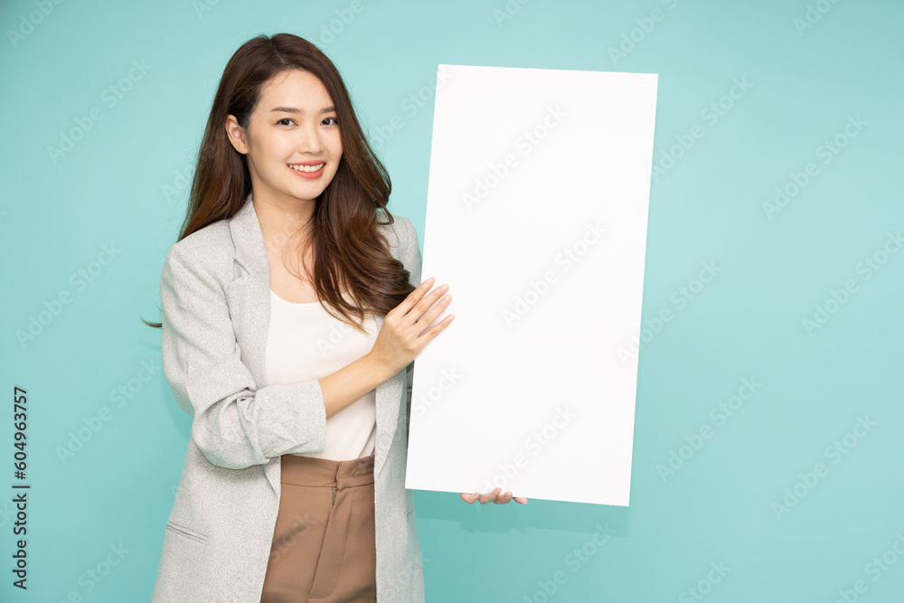 Asian business woman showing and holding blank white billboard isolated on green background Asian business woman showing and holding blank white billboard isolated on green background