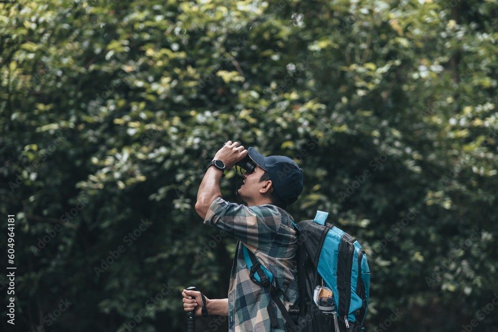 Hikers use binocular to see animals and view landscape  with backpacks in the forest. hiking and adventure concept.