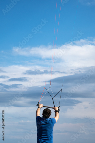 man holding sports kite flying, blue sky, summer