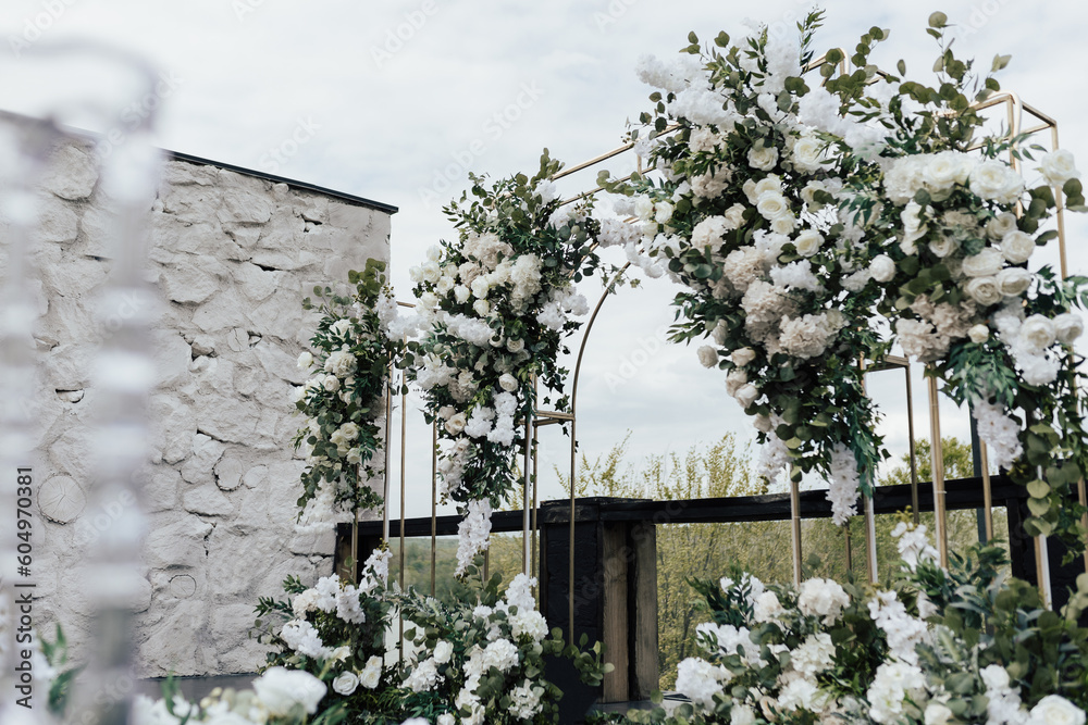 Wedding arch decorated with white flowers and greenery at the wedding ceremony in the fresh air.