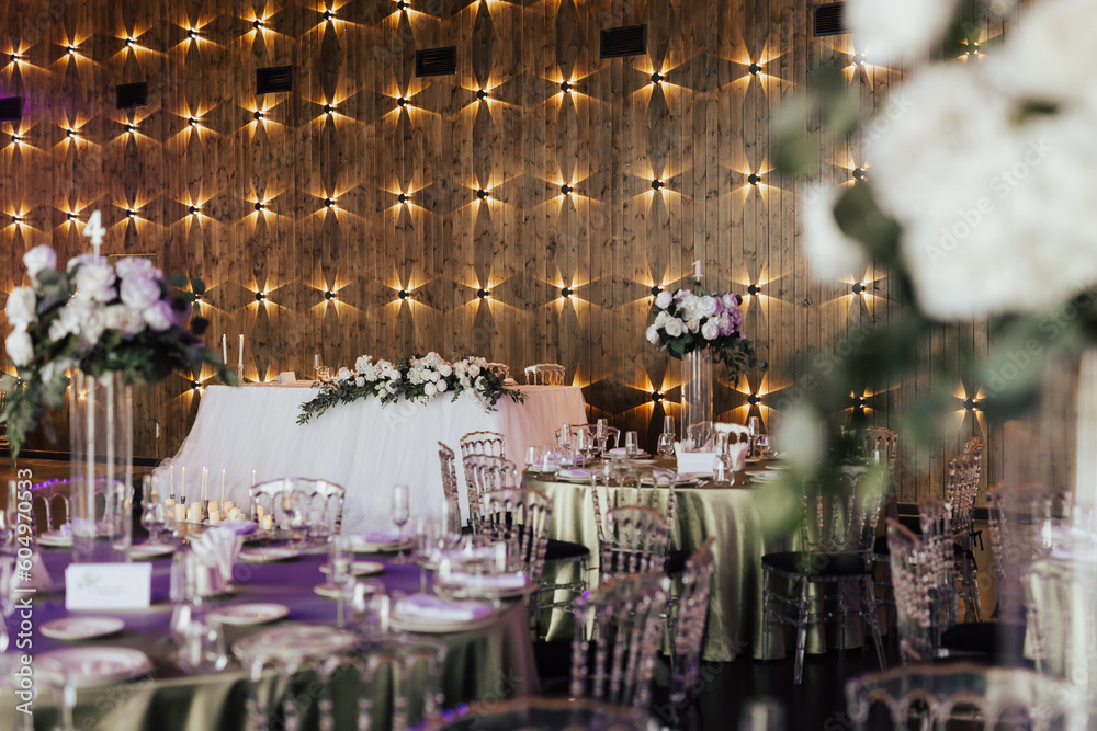 Round tables decoration with flower composition in center. Arrangements of tables at wedding reception.