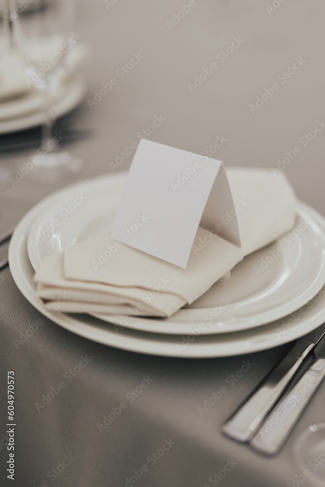 Table setting with white plate, glasses and cutlery on table. Table served for wedding banquet in restaurant.