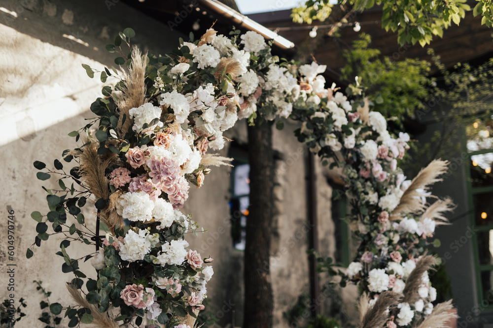 Wedding ceremony with round arch with floral arrangement in the fresh air at summer sunny day.