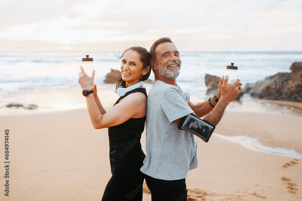 Happy mature caucasian man and woman in sportswear with phone, bottles of water have fun in morning - obrazy, fototapety, plakaty 